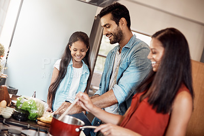 Buy stock photo Shot of a happy young family preparing a meal in the kitchen together at home