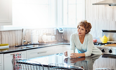 Buy stock photo Shot of a mature woman enjoying a warm beverage in the kitchen at home