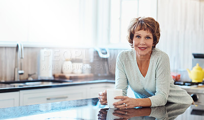 Buy stock photo Shot of a mature woman enjoying a warm beverage in the kitchen at home