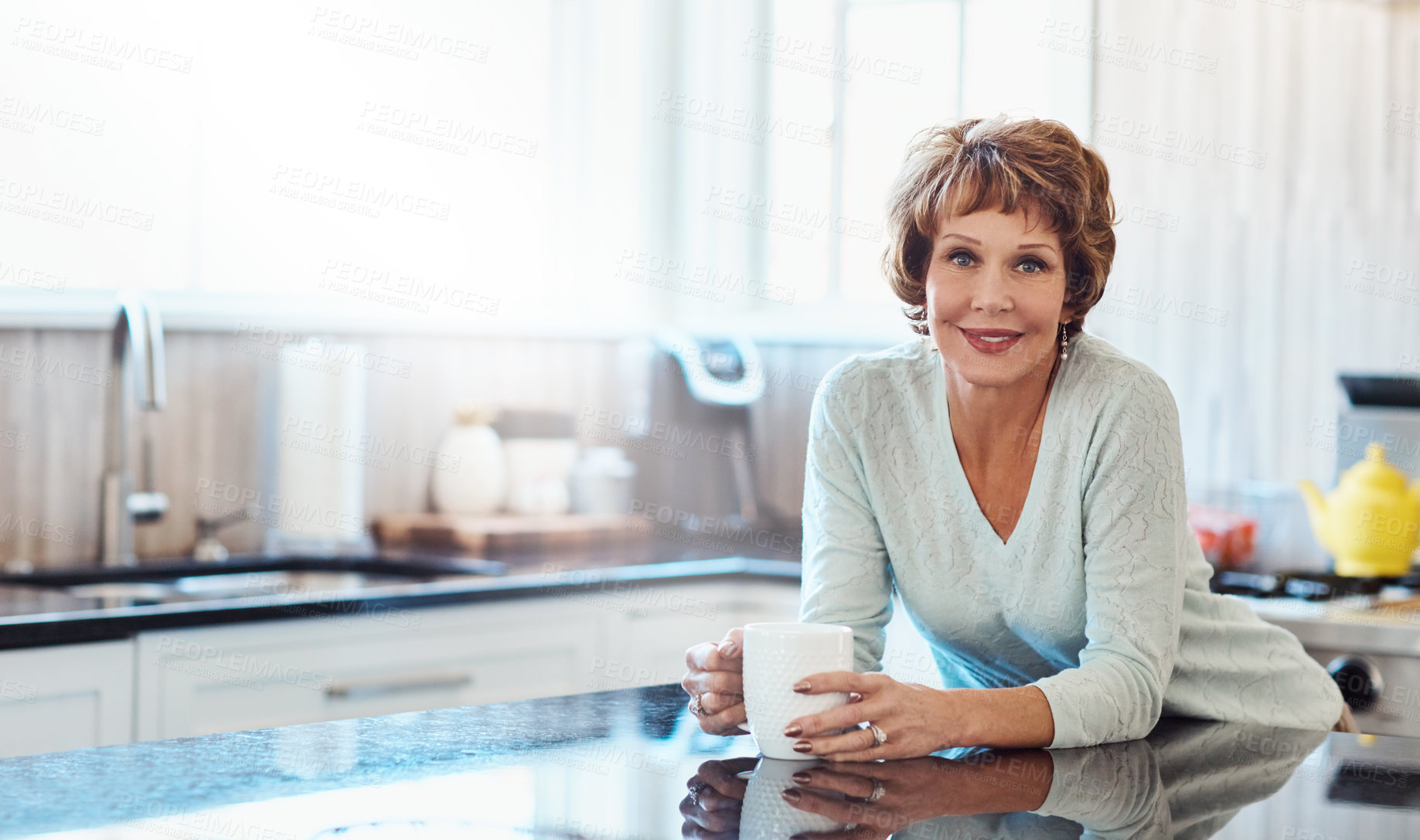 Buy stock photo Shot of a mature woman enjoying a warm beverage in the kitchen at home