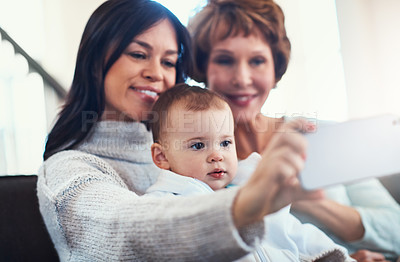 Buy stock photo Shot of a young woman taking selfies with her baby girl and mother at home