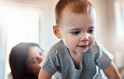 Buy stock photo Shot of an adorable baby girl crawling on a bed with her mother in the background