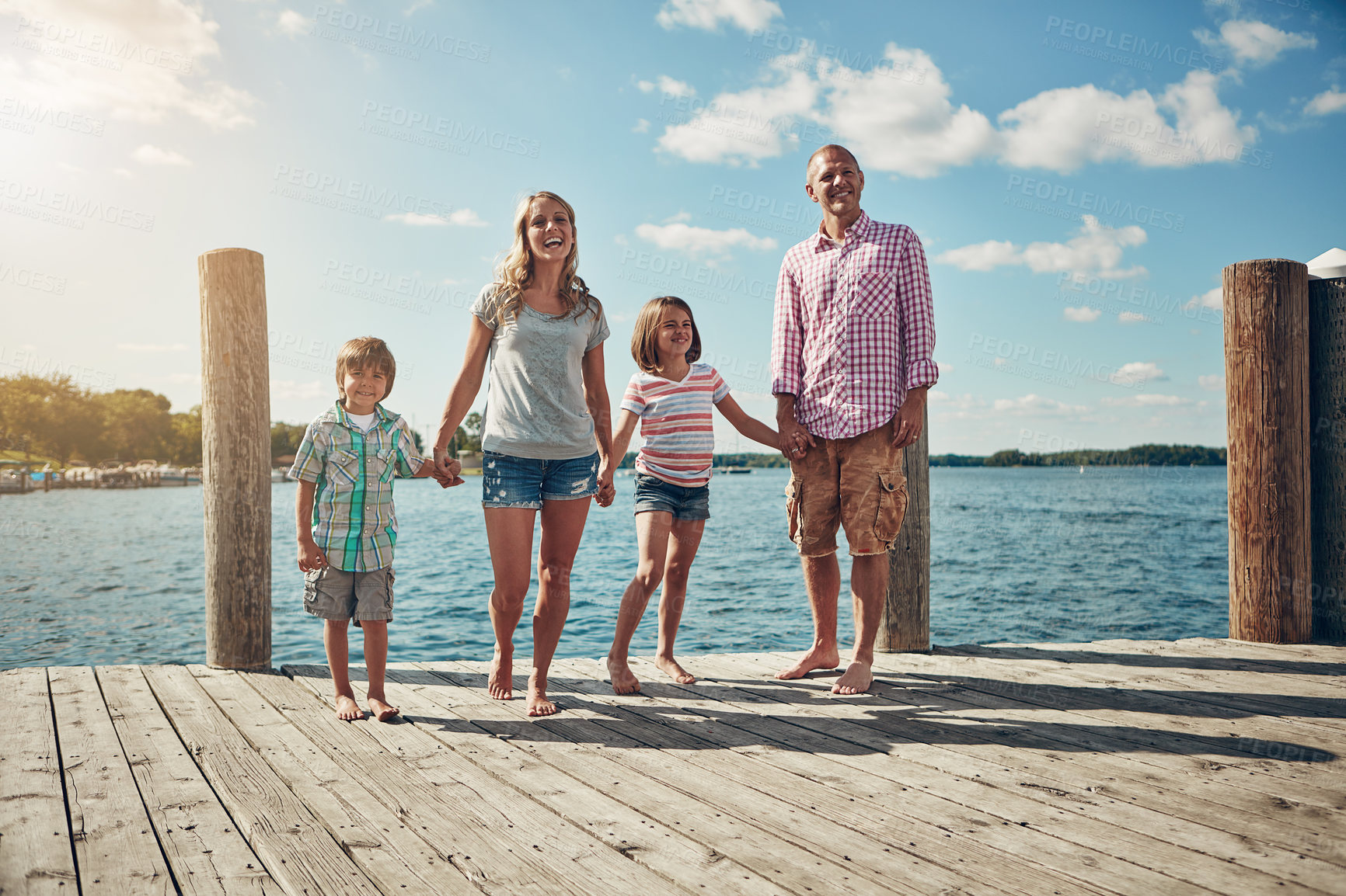 Buy stock photo Shot of a young family on a pier while out by the lake