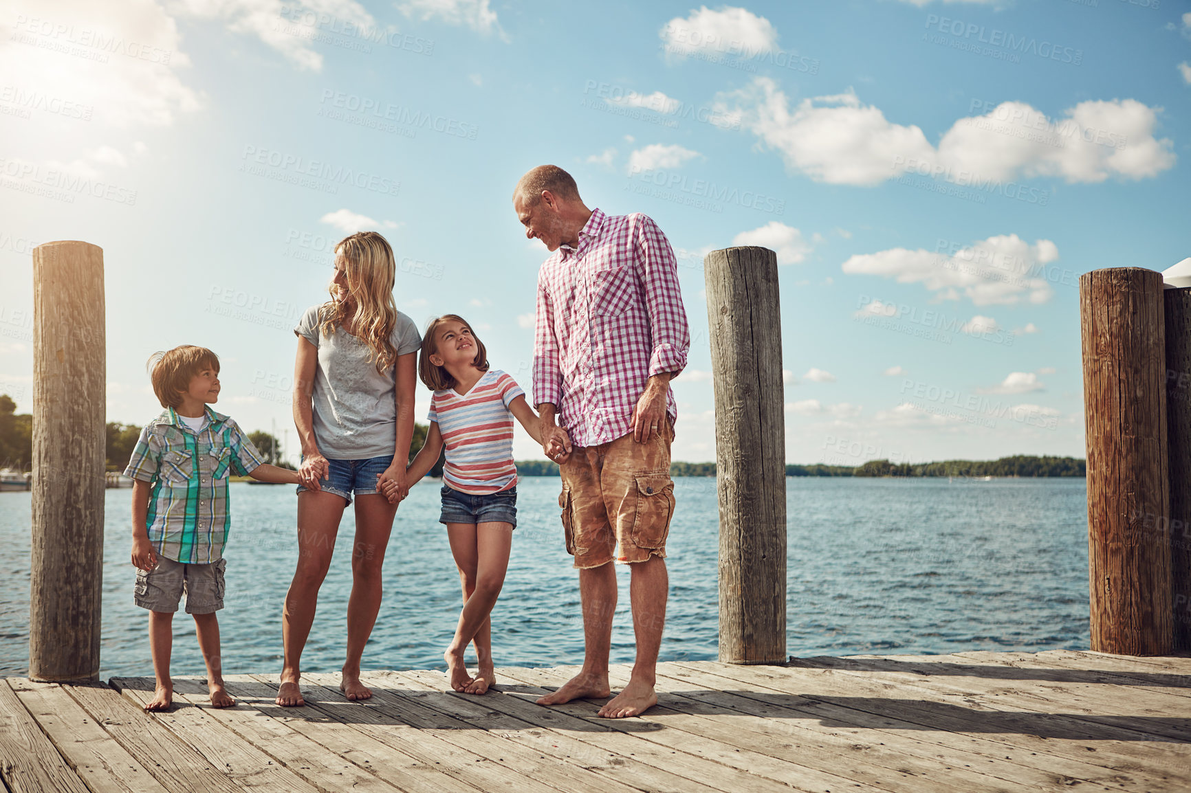 Buy stock photo Shot of a young family on a pier while out by the lake