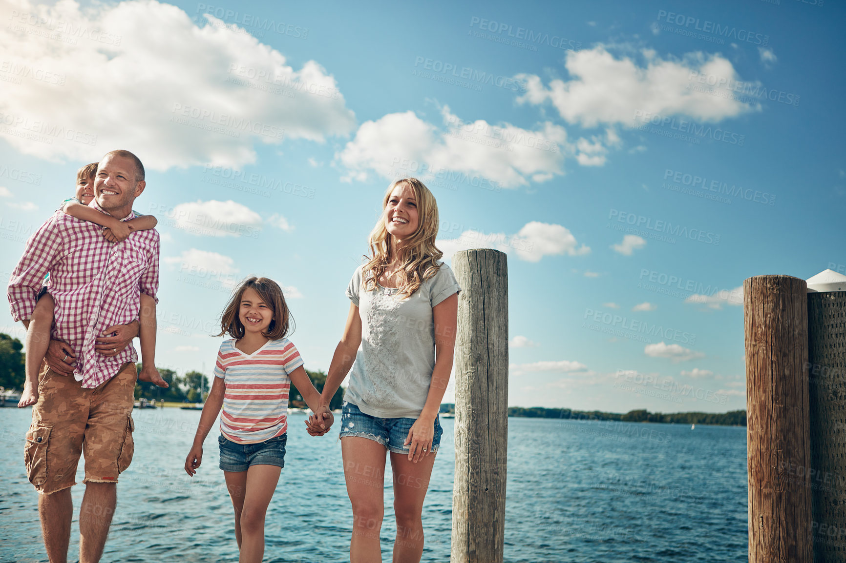 Buy stock photo Shot of a young family on a pier while out by the lake