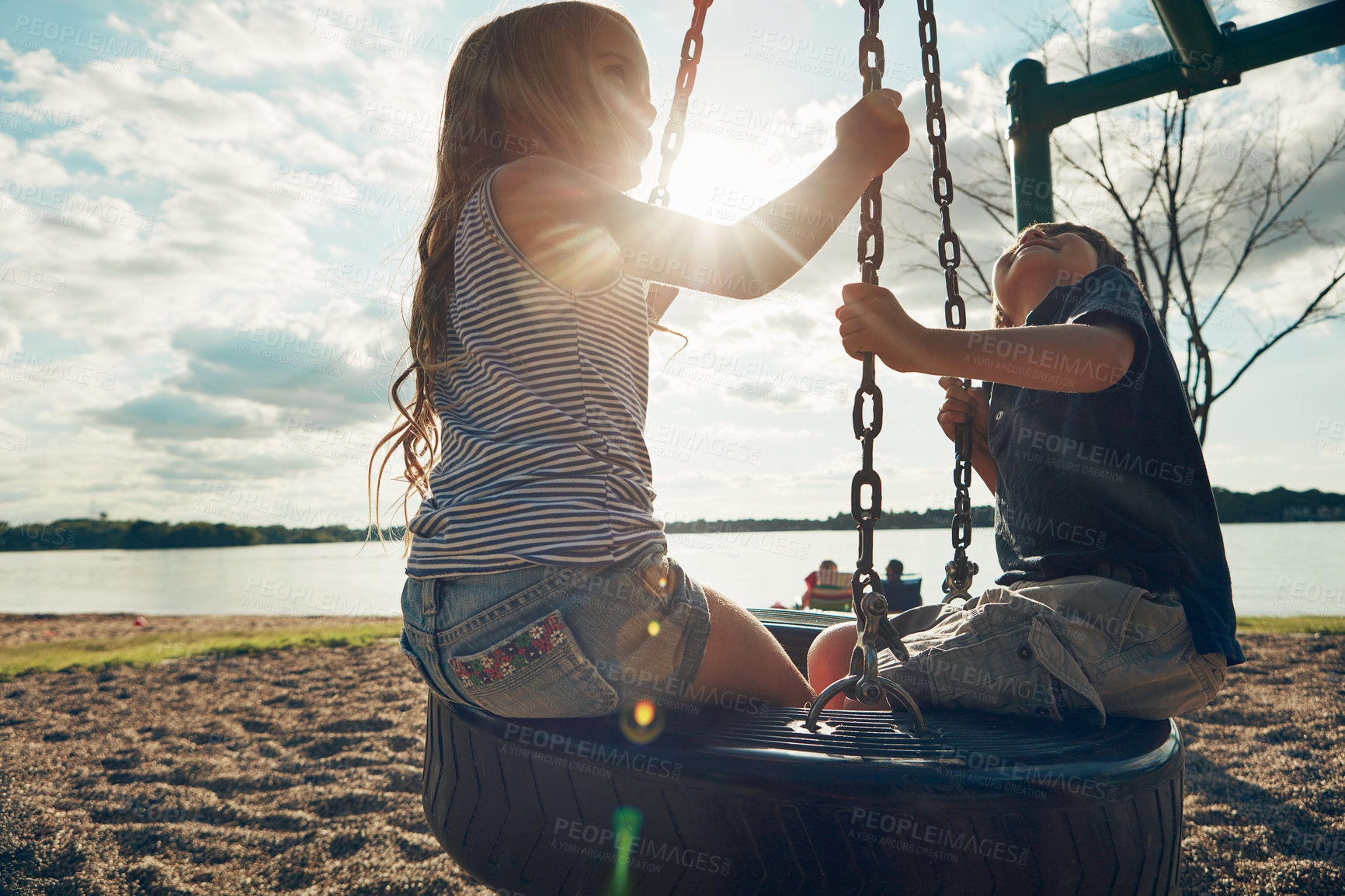 Buy stock photo Children, tyre swing and play in nature, bonding and friends at playground for game or adventure. Kids, lens flare and together for fun in backyard or freedom, siblings and connection on vacation