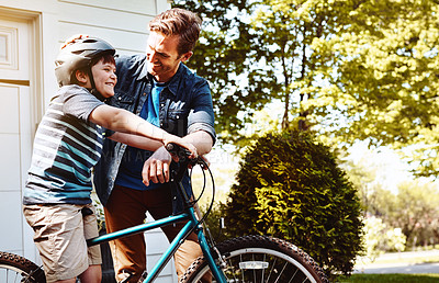 Buy stock photo Shot of a father teaching his son how to ride a bicycle