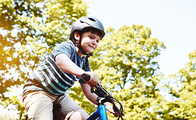 Buy stock photo Shot of a young boy riding his bicycle through his neighbourhood