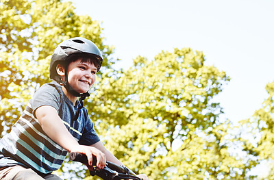 Buy stock photo Shot of a young boy riding his bicycle through his neighbourhood