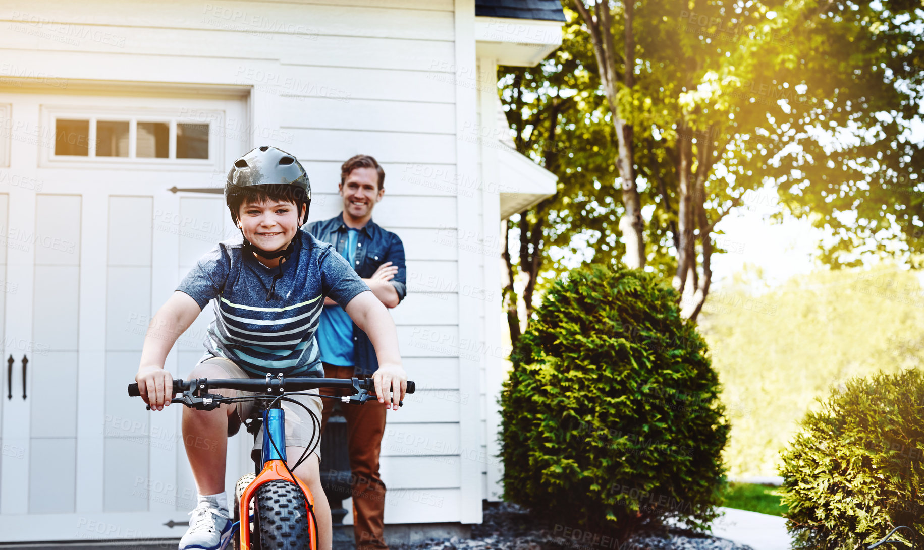 Buy stock photo Shot of a young boy riding a bicycle with his father in the background