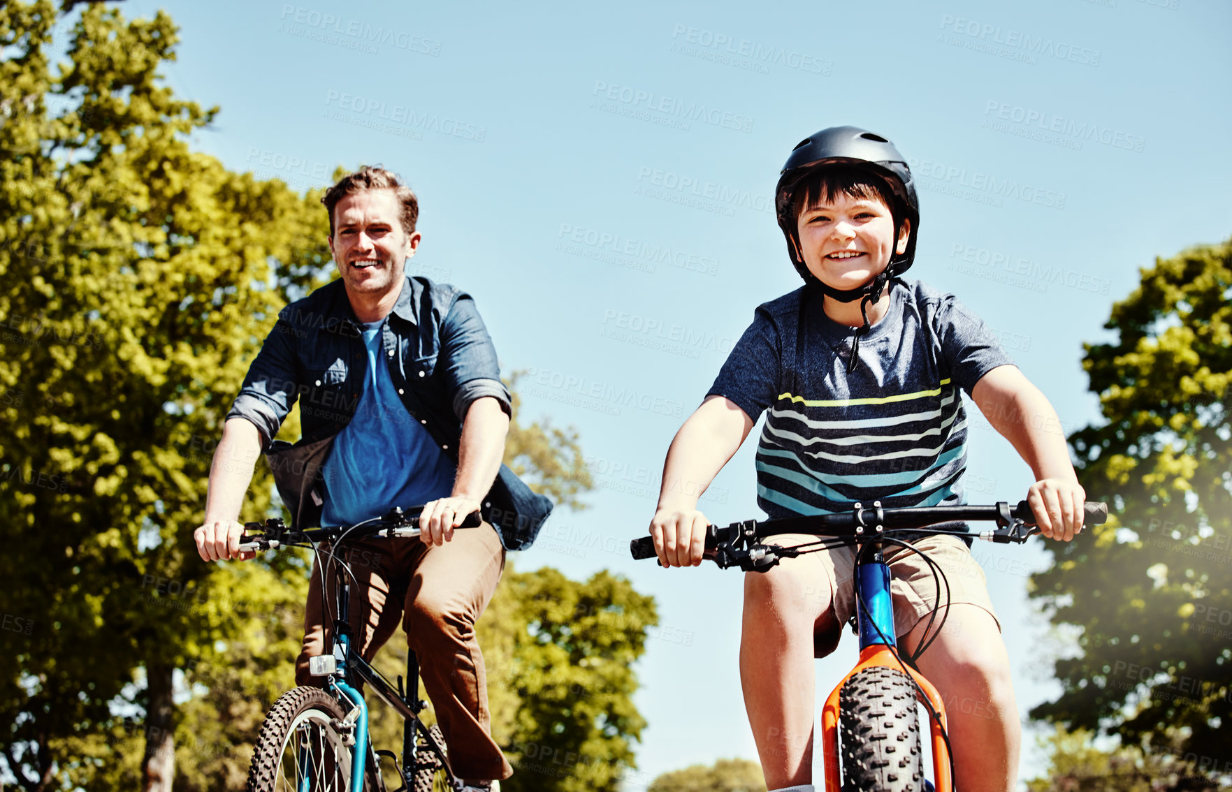 Buy stock photo Boy, happy and bike at park in summer with dad, bonding and love with space on vacation. People, father and child for cycling, ride bicycle or smile in portrait, outdoor and connection on holiday