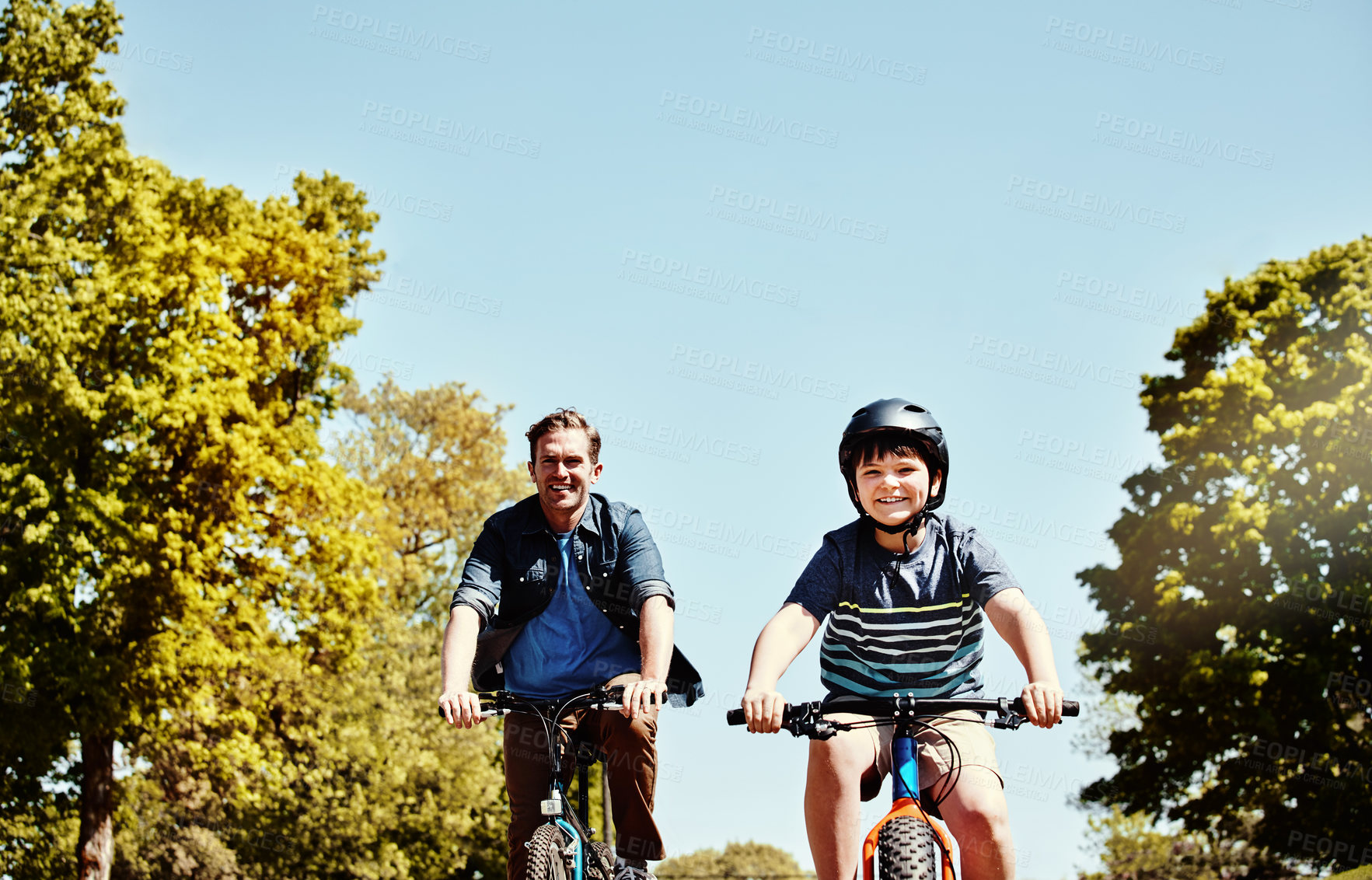 Buy stock photo Shot of a young boy and his father riding together on their bicycles