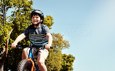 Buy stock photo Shot of a young boy riding his bicycle through his neighbourhood