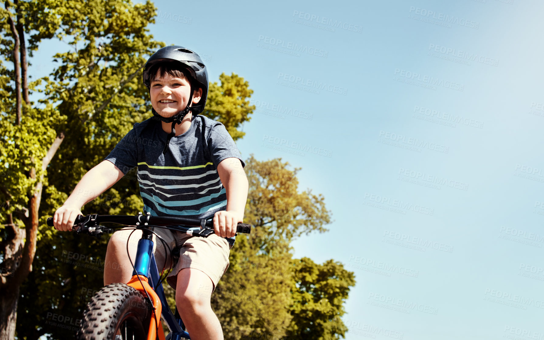 Buy stock photo Shot of a young boy riding his bicycle through his neighbourhood