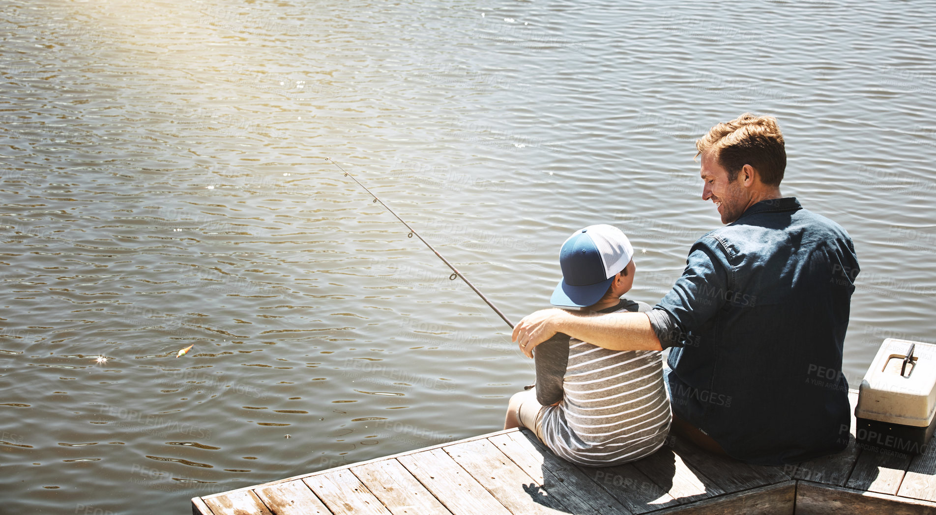 Buy stock photo Rear view shot of a father and his little son fishing together