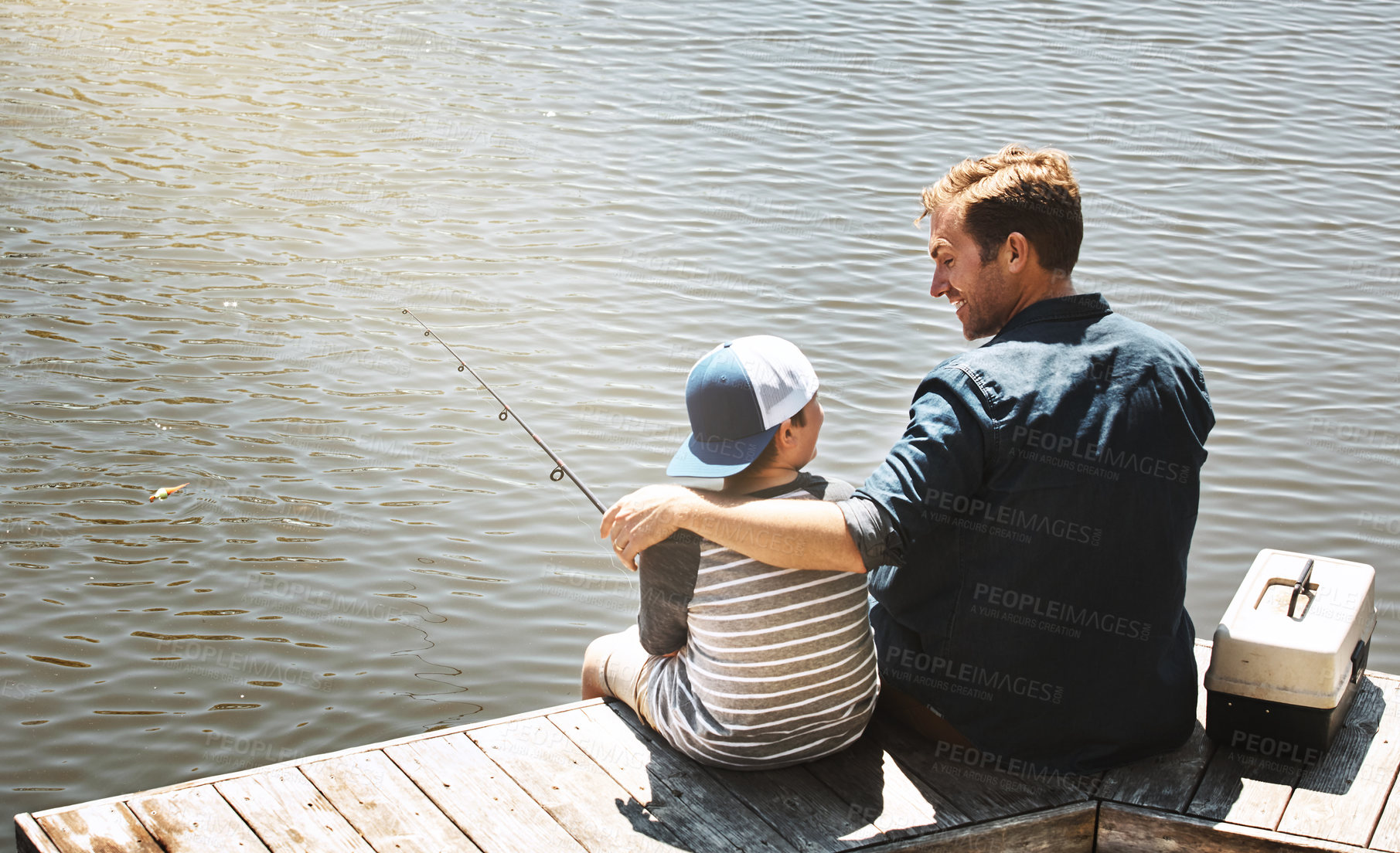 Buy stock photo Happy dad, back and fishing with son by lake, ocean or beach with rod together in nature. Father with child, kid or little boy with hug for bonding, lesson or tips to catch sea creatures by water