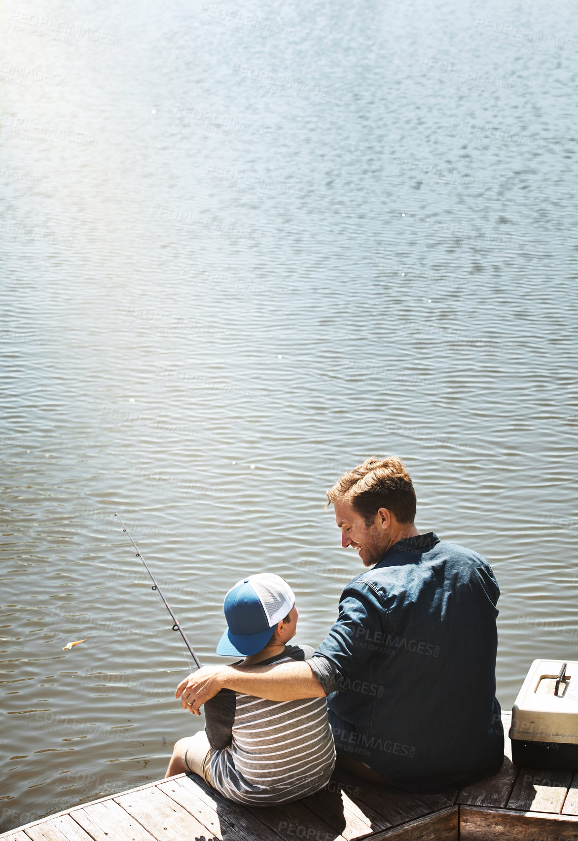 Buy stock photo Happy father, back and fishing with child by lake, ocean or beach with rod together in nature. Dad with son, kid or little boy with hug for bonding, lesson or tips to catch sea creatures by water