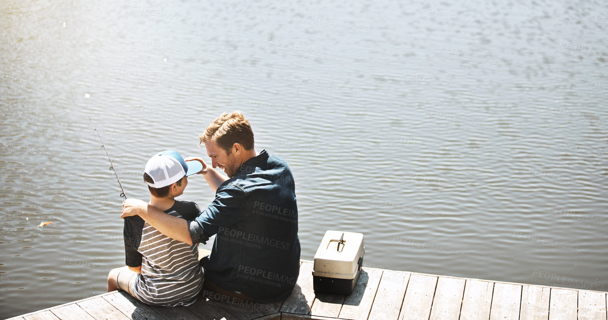 Buy stock photo Happy father, back and bonding with son or fishing rod by lake, ocean or beach together in nature. Dad with young child, kid or little boy with hug for lesson or tips to catch sea creatures by water