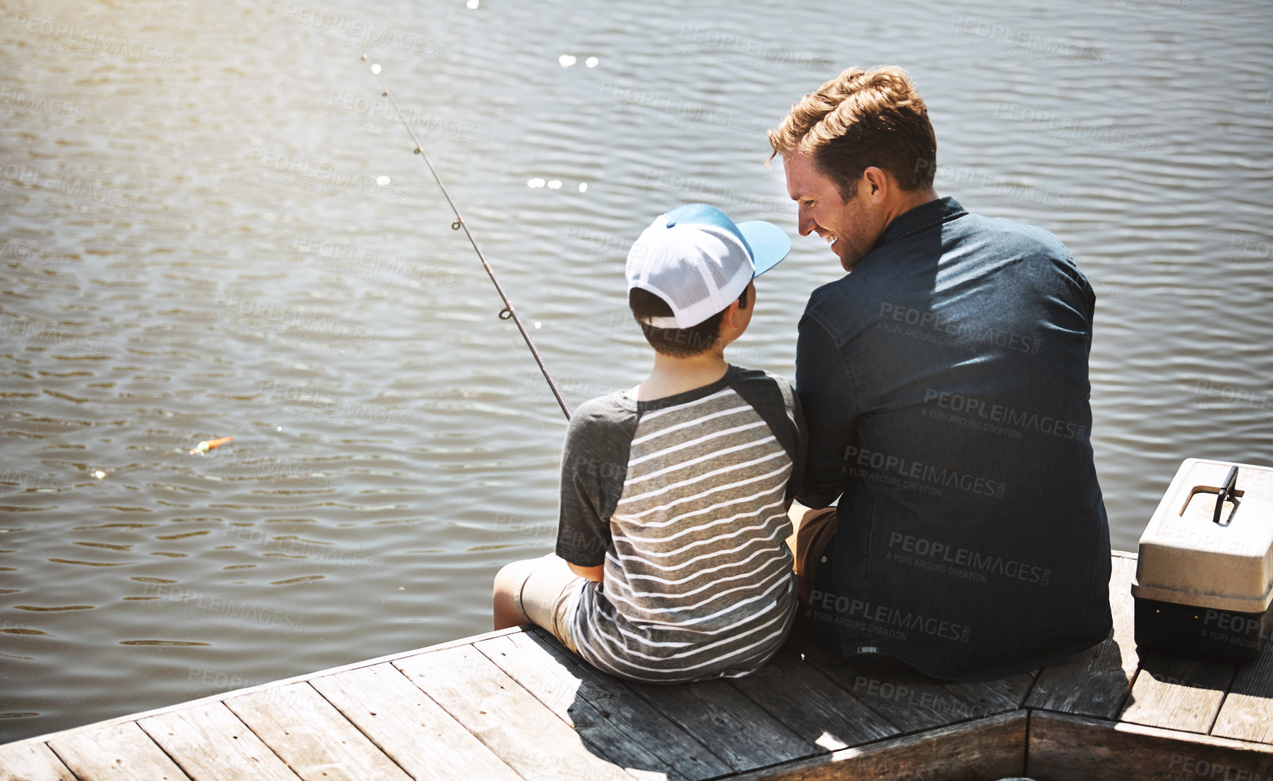 Buy stock photo Happy father, back and teaching kid with fishing rod by lake, ocean or beach together in nature. Dad with son, young child or little boy with hug for lesson or tips to catch sea creatures by water