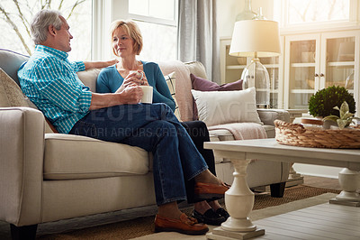 Buy stock photo Senior couple, coffee and talk on sofa in conversation, relax or happy memory in home living room. Old man, elderly woman and chat for bonding with tea, love or story in retirement on couch in house