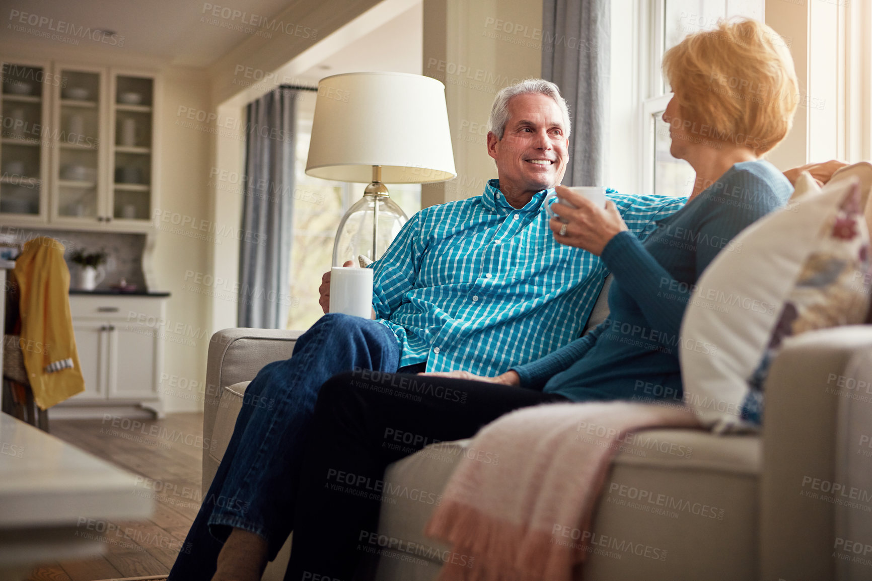 Buy stock photo Senior couple, coffee and smile on couch in conversation, relax or happy memory in home living room. Old man, elderly woman and chat for bonding with tea, love or story in retirement on sofa in house