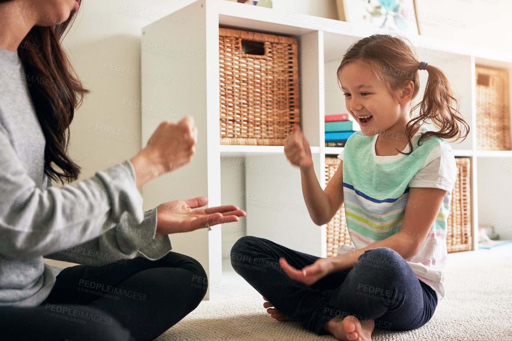 Buy stock photo Shot of a little girl playing rock, paper, scissors with her mother at home