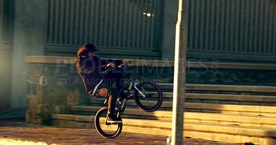 Buy stock photo Full length shot of a young male BMX rider doing tricks around the city