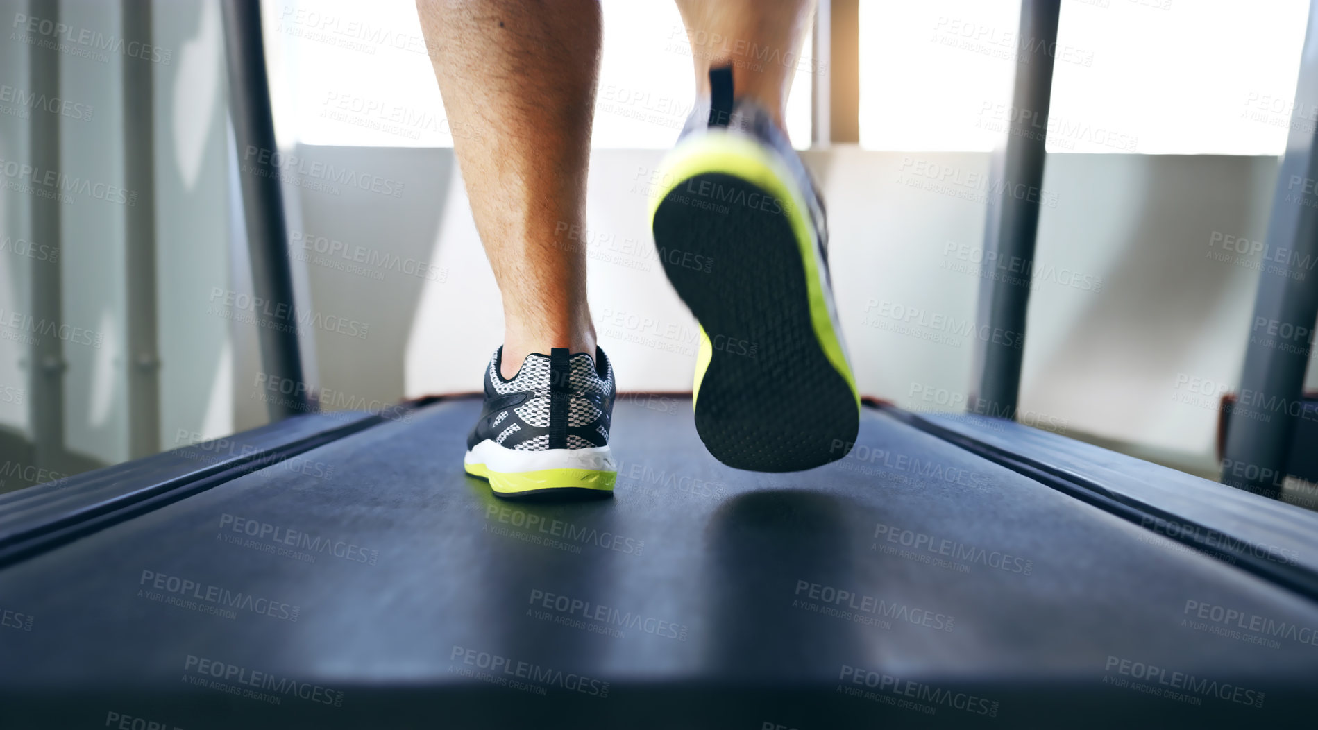 Buy stock photo Cropped shot of an unrecognizable man jogging on a treadmill in the gym