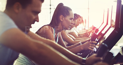 Buy stock photo Cropped shot of a group of young people working out on elliptical machines in the gym