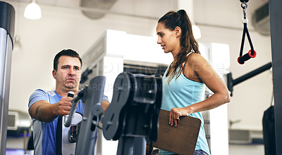 Buy stock photo Cropped shot of a female fitness instructor taking her male client through a workout in the gym