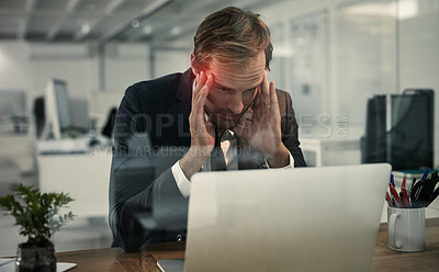 Buy stock photo Shot of a businessman looking stressed while working at his laptop