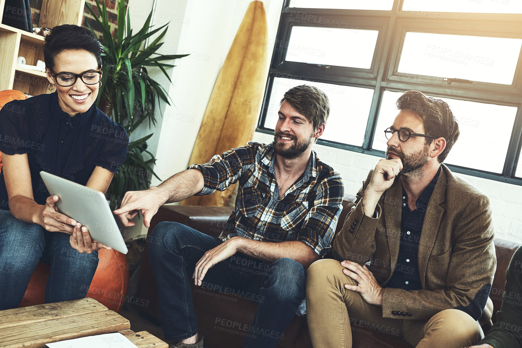 Buy stock photo Shot of a group of designers using a tablet in their brainstorming session