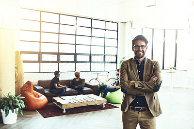 Buy stock photo Shot of a young designer standing in a office with his colleagues in the background