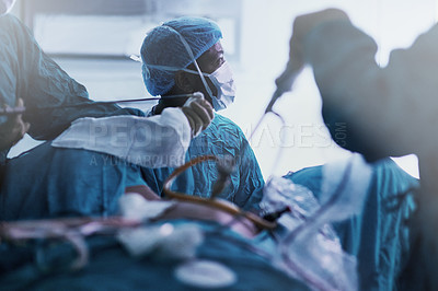 Buy stock photo Shot of a dedicated team of young surgeons performing surgery on a patient in an operating room