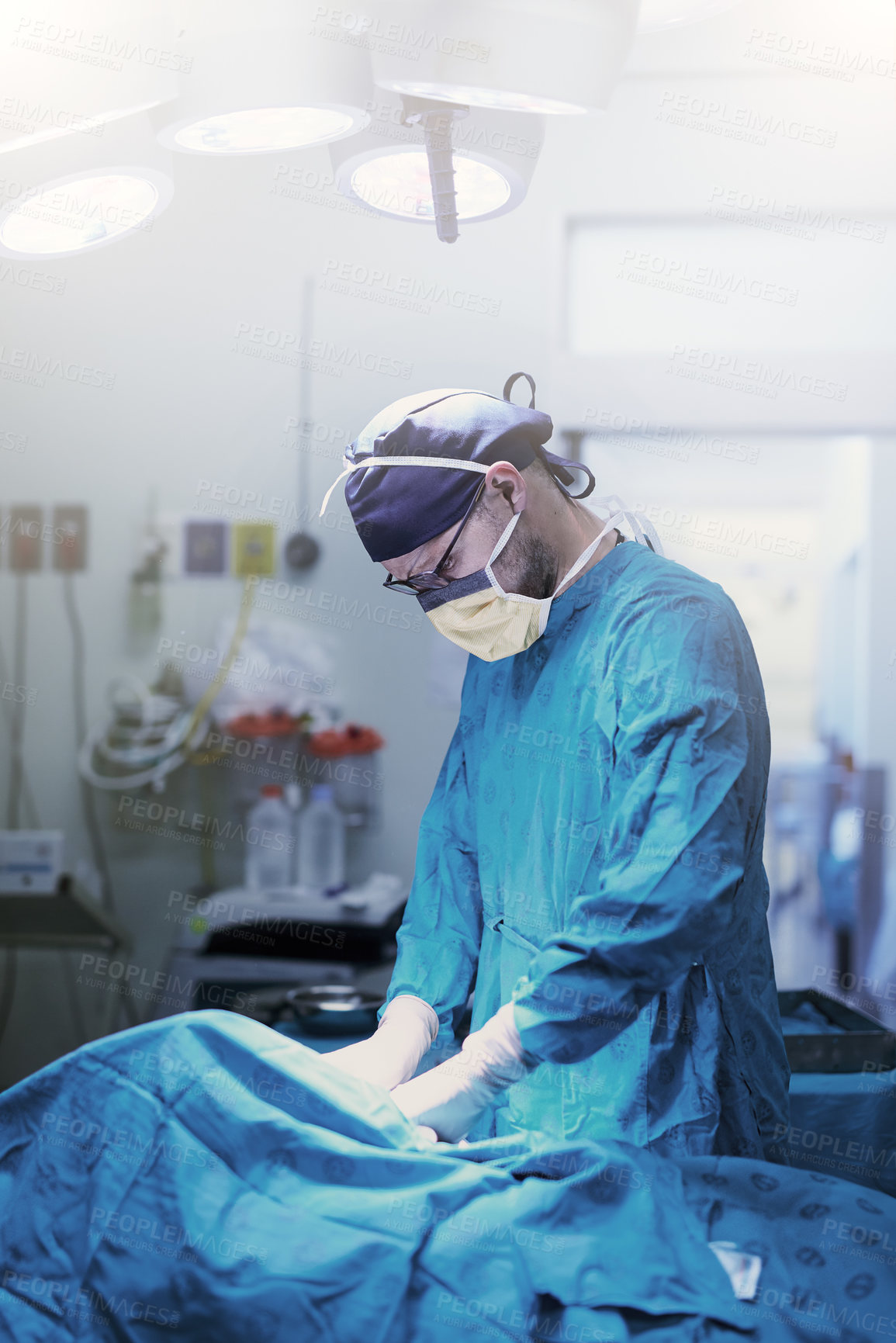 Buy stock photo Shot of a focused young surgeon performing surgery on a patient in an operating room