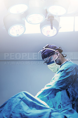 Buy stock photo Shot of a focused young surgeon performing surgery on a patient in an operating room