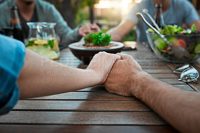 Buy stock photo Cropped shot of two unrecognizable people holding hands around a table outside in a garden