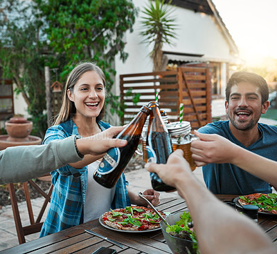 Buy stock photo Shot of a group of young friends holding up drinks and toasting outside around a table to celebrate their friendship