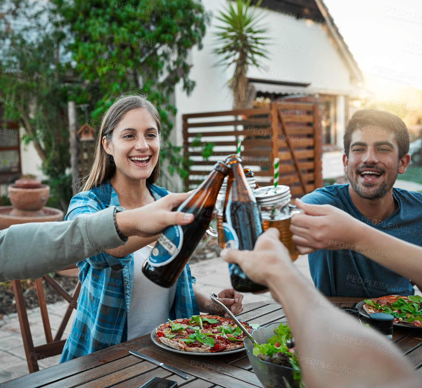 Buy stock photo Lunch, alcohol and people in garden for cheers, celebration and connection for bonding together. Outdoor, smile and friends with beer bottle in social gathering, toast and salad as food for nutrition