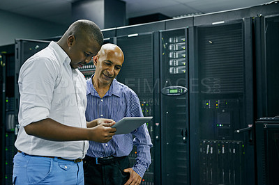 Buy stock photo Shot of two IT technicians using a digital tablet while working in a data center