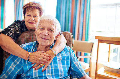 Buy stock photo Shot of a cheerful elderly couple holding each other while looking at the camera inside of a building