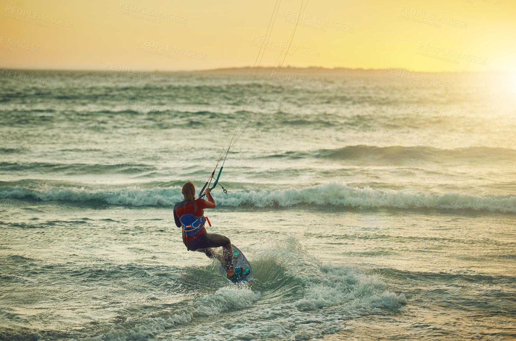 Buy stock photo Rearview shot of a young woman kitesurfing at the beach