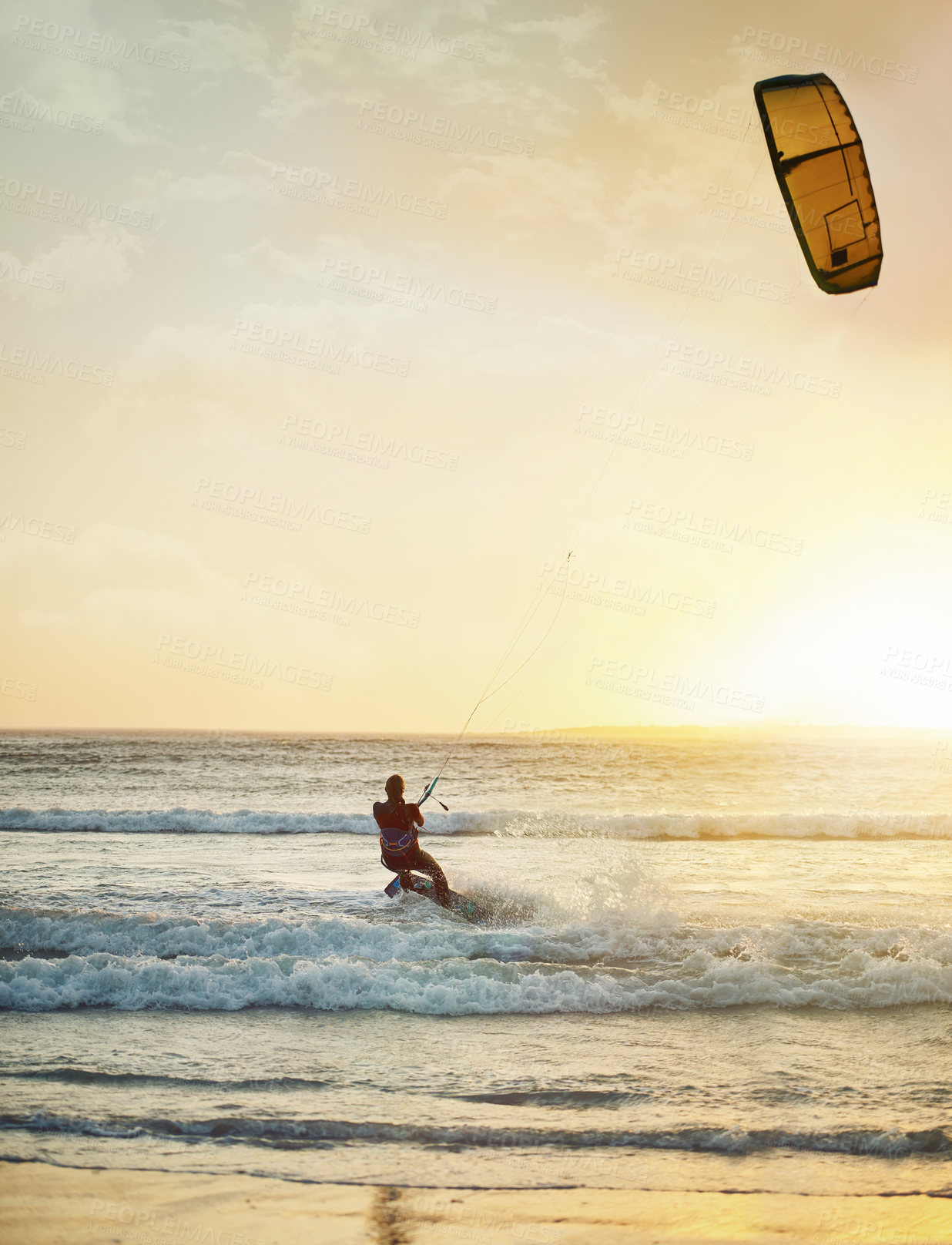 Buy stock photo Rearview shot of a young woman kitesurfing at the beach