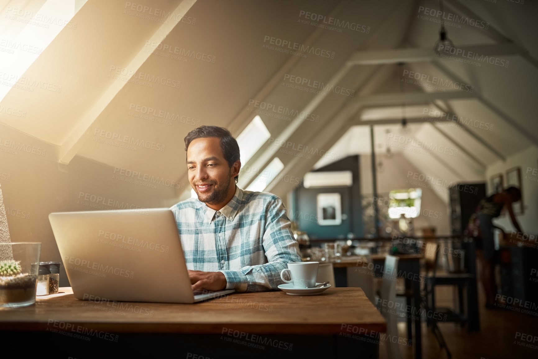 Buy stock photo Shot of a young entrepreneur using his laptop in a coffee shop