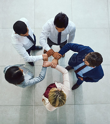 Buy stock photo High angle shot of a diverse group of businesspeople joining their hands together in unity