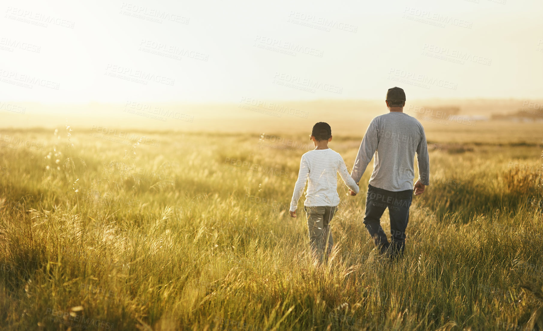 Buy stock photo Back, outdoor and father with son, walking or adventure with sunshine, getaway trip or bonding together. Family, single parent or dad with kid, field or childhood with weekend break, nature or travel