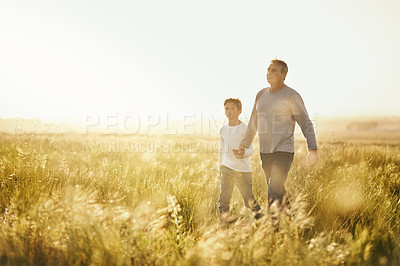 Buy stock photo Shot of a man taking his son for a walk out on an open field