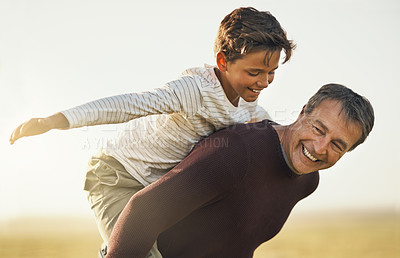 Buy stock photo Shot of a father and son having a good time as the father piggybacks his son