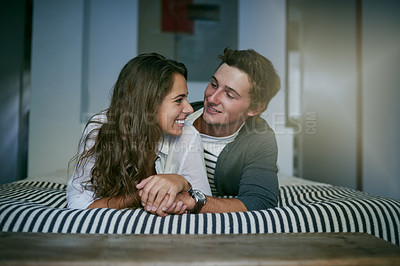 Buy stock photo Shot of an affectionate young couple lying on bed