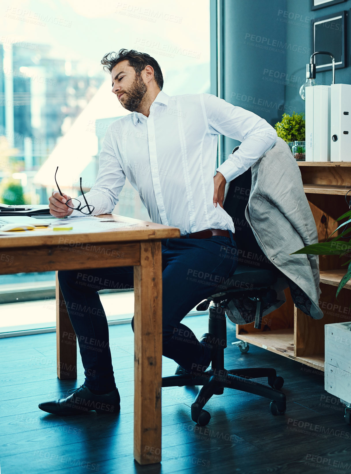 Buy stock photo Frustrated businessman, back injury and desk with pain from accident, inflammation or bad posture at office. Young man or employee with sore spine, ache or bruise on chair in discomfort at workplace